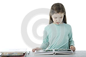 Little girl at the table in school on white