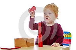 The little girl at the table works with the Montessori material.