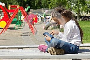 Little girl with a tablet in hands, attentively looking at the tablet screen