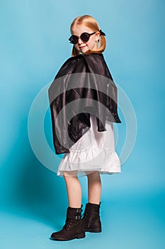 Little girl with tails in stylish clothes on blue background