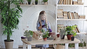 A little girl takes care of flowers, looks and admires a flower.