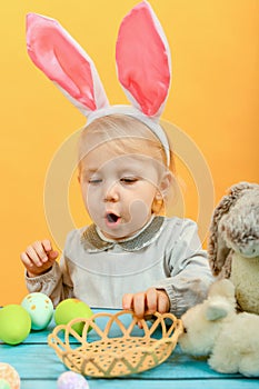 A little girl takes out painted Easter eggs from a basket and sh