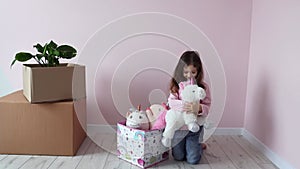 A little girl takes out toys from a box in his new room in a new house. A little girl is happy to move into her new room