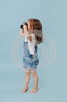 Little girl is taking an image with a vintage mirrored camera over blue