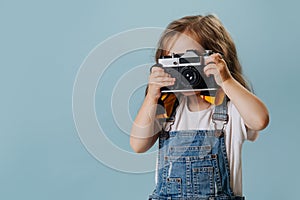 Little girl is taking an image with a vintage mirrored camera over blue