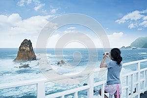 Little girl taking a photo of Papuma beach