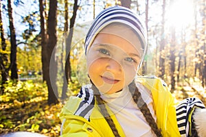 Little girl taking selfie with her dog at autumn park. Child posing with jack russell terrier for a picture on the