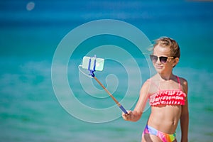 Little girl taking selfie portrait with her smartphone on the beach. Adorable model making selfportrait background