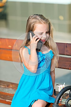 Little girl talk on cell phone on park bench, summer