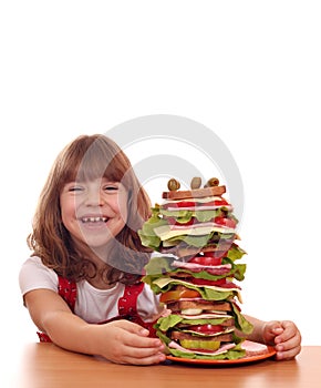 Little girl with tall sandwich on table