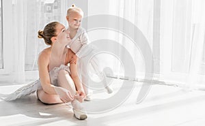 Little girl is taught how to tie ballet pointe shoes