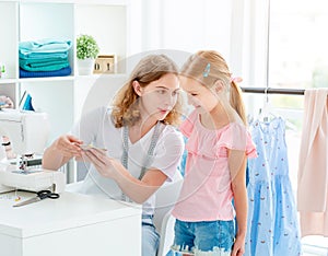 Little girl is taught to sew