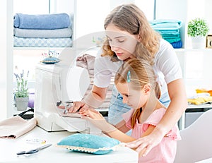 Little girl is taught to sew