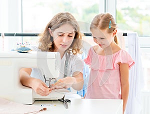 Little girl is taught to sew