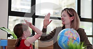 Little girl and teacher giving high five in classroom near globe 4k movie slow motion