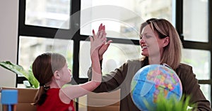 Little girl and teacher giving high five in classroom near globe 4k movie slow motion