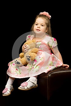 Little girl with a teddy bear on a black background.