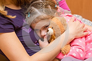 Little girl with teddy bear clung to her mother with a sad expression on his face