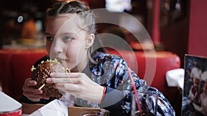 Little girl teenager eats a burger in fast food. hamburger and french fries