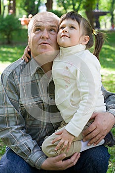 Little girl tenderly embraces grandfather and sits photo