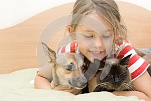 Little girl tenderly embraces pets