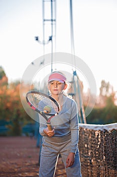 A little girl, tennis player, actively playing, throwing the ball on a tennis racket.