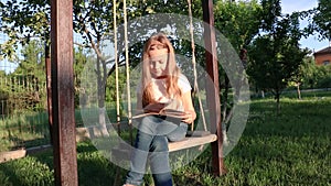 Little girl thinking and writing on nest swing