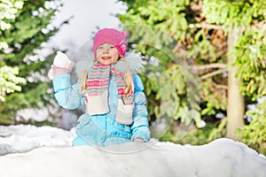 Little girl throw snowball hiding behind snow wall