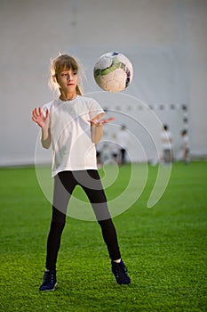 A little girl throwing the ball on the field playing football