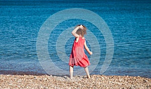 Little girl throwing pebbles at sea