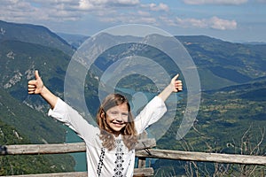 Little girl with thumbs up on mountain top