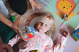 Little girl toddler with parents playing with blocks with numbers in children`s room at home