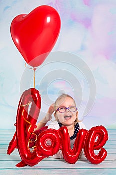 Little girl toddler with red heart balloonand love sign. Valentines day concept