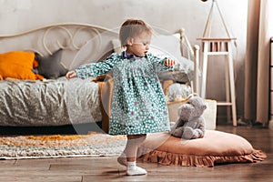 Little girl Todler in dress plays in the children`s room. Soft pastel colors. Children`s room interior in daylight