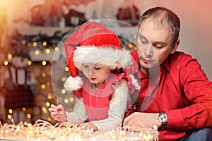 Little girl together with dad write a letter of wish to Santa Claus. Christmas. New Year