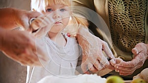 A little girl touching the dough. Shaking off flour from the hands