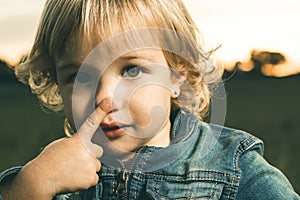 Little girl touching her nose with a finger