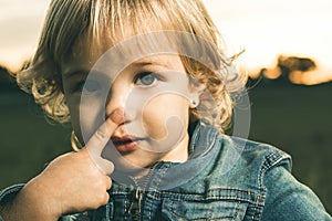 Little girl touching her nose with a finger photo