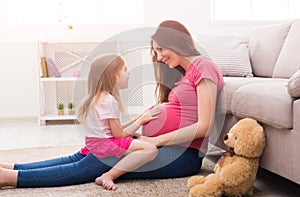 Little girl touching her pregnant mother belly