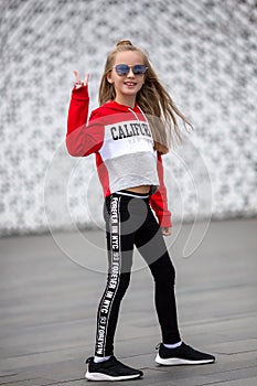 Little girl in a tracksuit is dancing modern dance on the street. Young urban hip hop dancer
