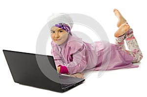 Little girl in traditional muslim clothes with laptop