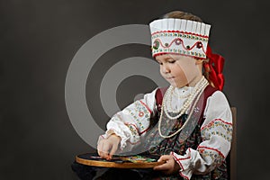Little girl in the traditional russian sarafan during embroidering.