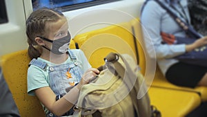 Little girl travel caucasian ride at overground train airtrain with wearing protective medical red mask. Child baby at