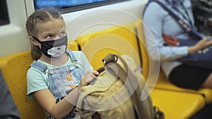 Little girl travel caucasian ride at overground train airtrain with wearing protective medical red mask. Child baby at