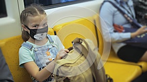 Little girl travel caucasian ride at overground train airtrain with wearing protective medical red mask. Child baby at