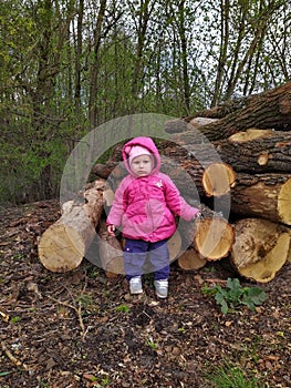 Little girl before tree timbers near forest