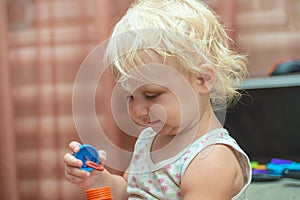 A little girl tries to inflate soapy water balls. Child and soap bubbles