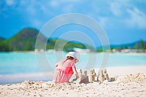 Little adorable girl at tropical beach making sand castle