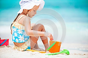 Little girl at tropical white beach making sand castle