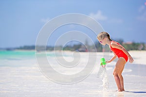 Little girl at tropical white beach making sand castle